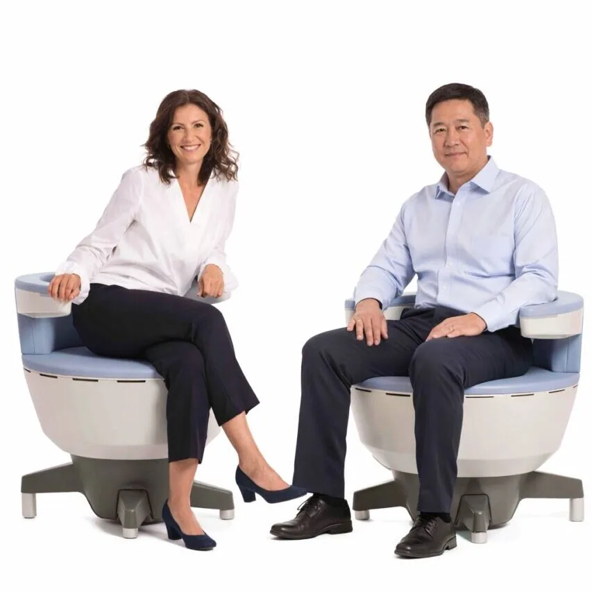 A woman and a man seated fully clothed on EMSELLA pelvic-floor therapy chairs at Holistique Medical Center, Bellevue
