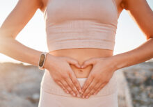 Woman, heart and hands on stomach for fitness, weightloss diet or holistic gut wellness. Closeup female abdomen, love fingers or belly emoji of body digestion, skincare and healthy exercise in nature.