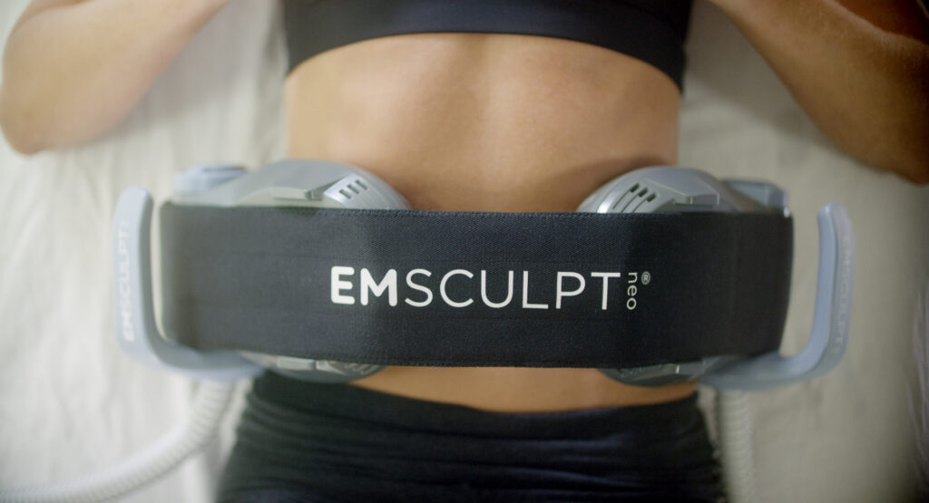 EMSCULPT NEO device applied to the abdomen during non-invasive muscle stimulation treatment at Holistique Medical Center