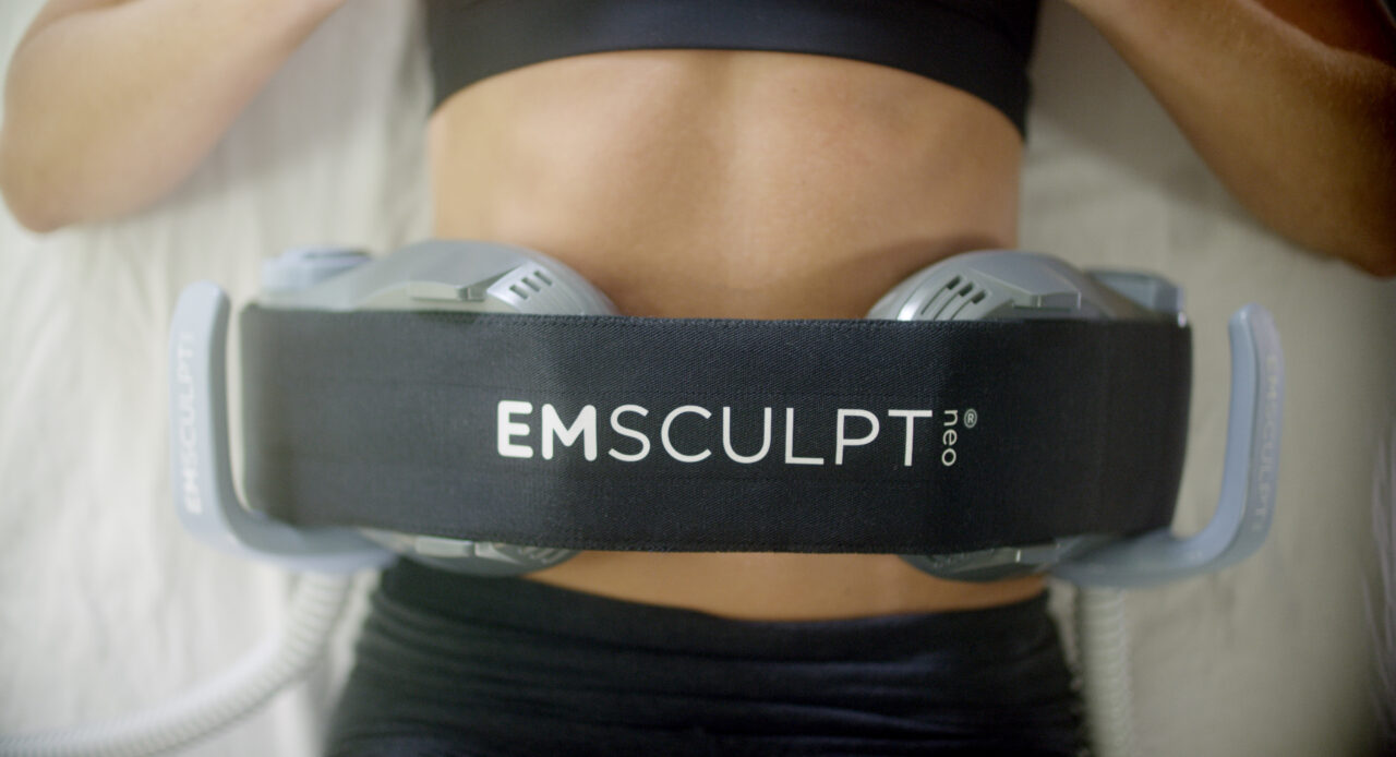 EMSCULPT NEO device applied to the abdomen during non-invasive muscle stimulation treatment at Holistique Medical Center